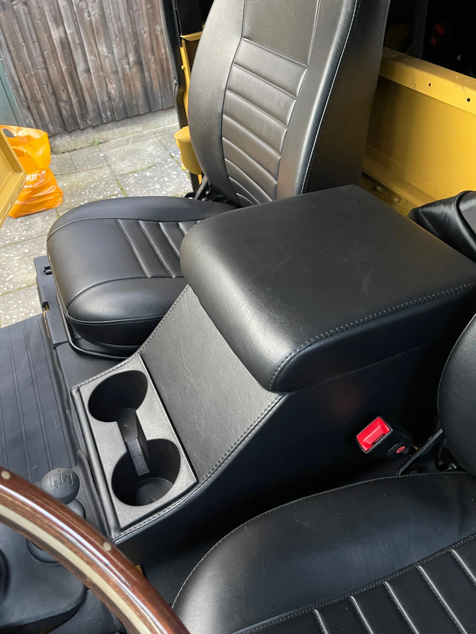 Black centre cubby box and cup holders between the Defender front seats