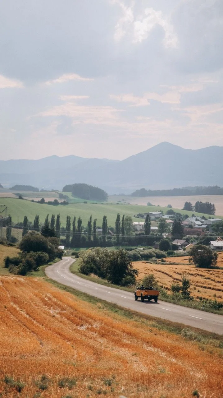 Defender 110 driving along a country road through a wide valley