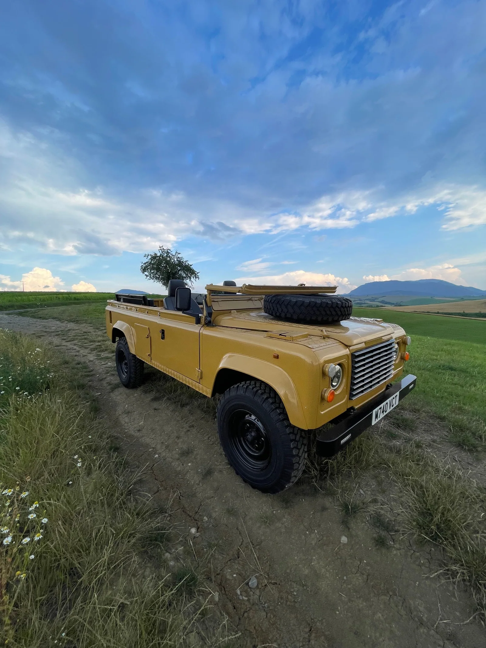 Wide front three-quarter view of the open Defender in countryside