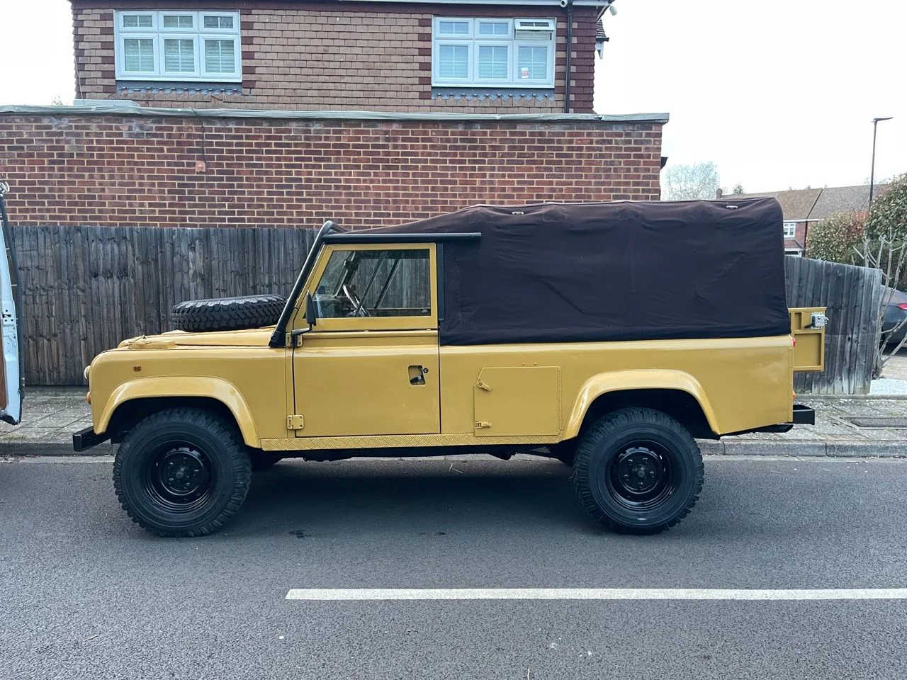 Full side profile of the Defender 110 with brown soft top fitted
